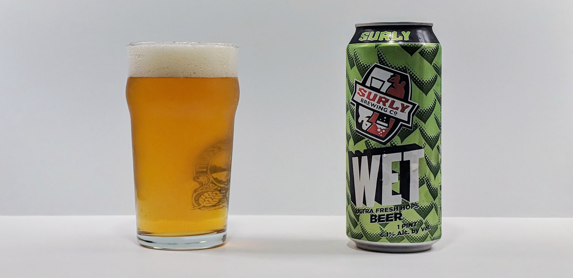 A glass of Surly Wet IPA with a bright amber color and thick layer of powder - Wet: Explosive Seasonal Flavors