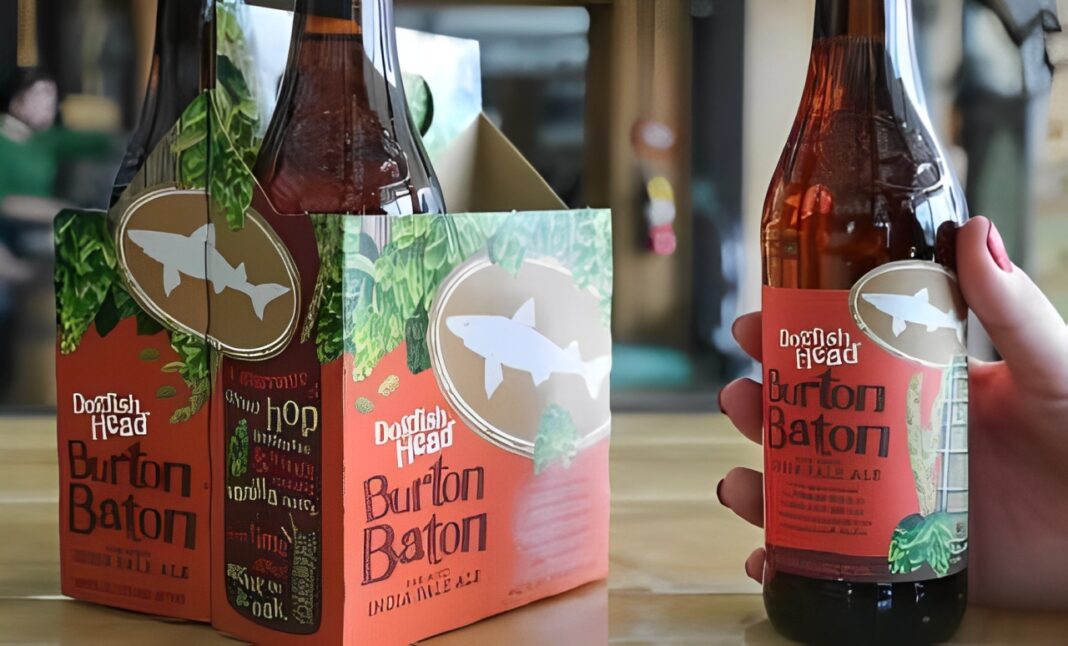 Dogfish Head's Burton Baton beer sits on a dark wood table, warm lighting giving depth to the image