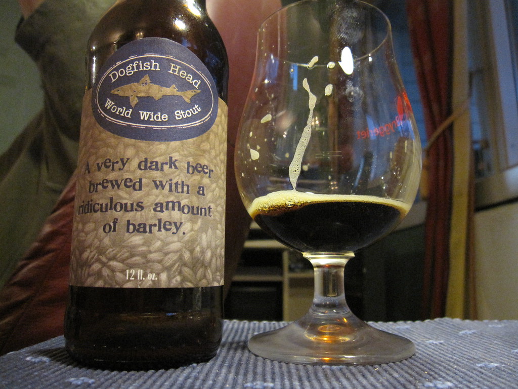 Luxurious black label World Wide Stout bottle, set on dark wood background.