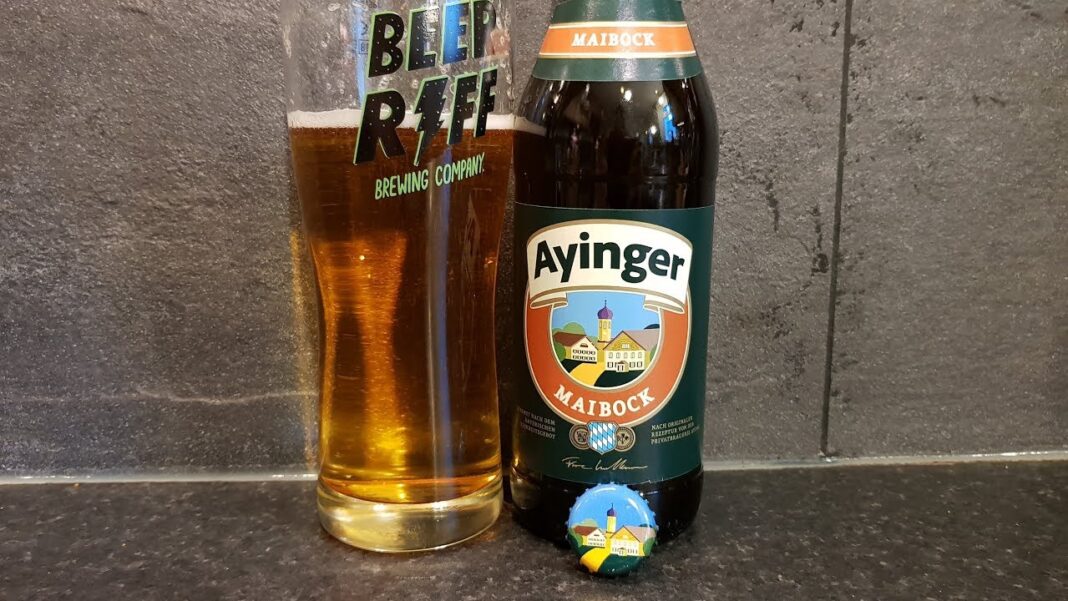 Clear horizontal shot of Ayinger Maibock beer bottle, showing amber color