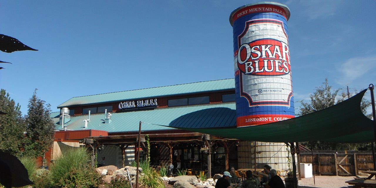 Image of Oskar Blues Grill Brew outside the colorful house - Mama's Little Yella Pils: Golden Gem to Refresh the Soul