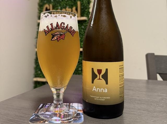 Anna has a simple design with a dark yellow color scheme and the brewery logo in the center - Anna: The Elevation of Specialty Saison