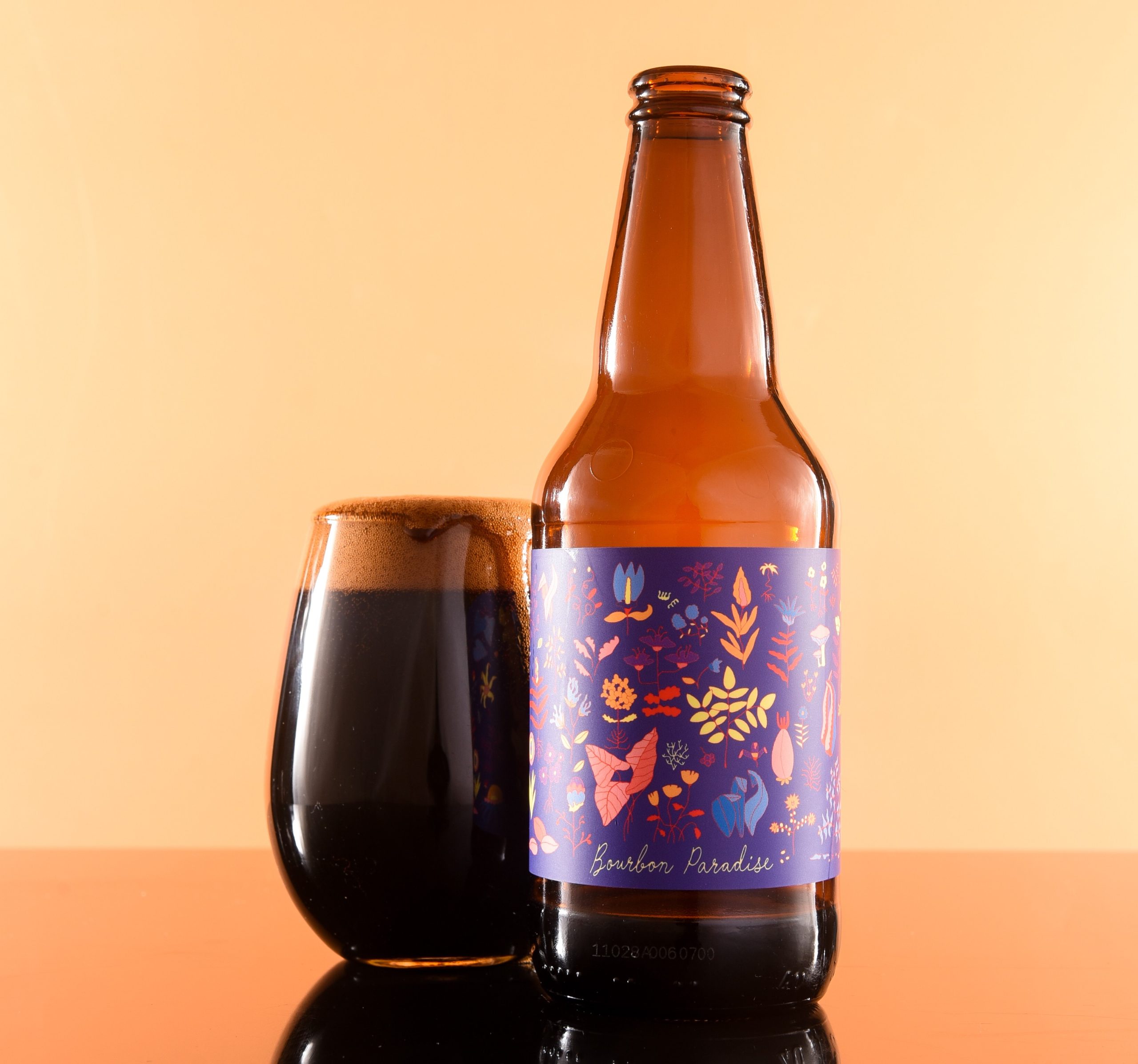 Das Bild zeigt eine Pastry Stout Bierflasche mit einem Design, das sehr niedliche, schuppenartige Details aufweist – Bourbon Paradise: The Breath of Oak and a Wordless Story.