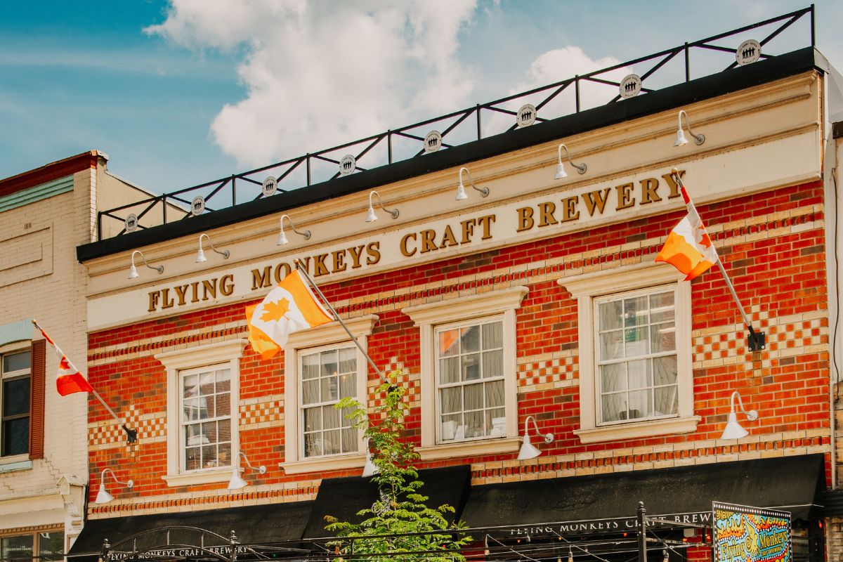 The image shows the glass-fronted building housing the Flying Monkeys Craft Brewery - Quantum Hugs Cold IPA: Where Excellence is Encapsulated.